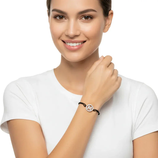 Woman wearing silver diamond initial M bracelet on black cord, minimalist jewelry