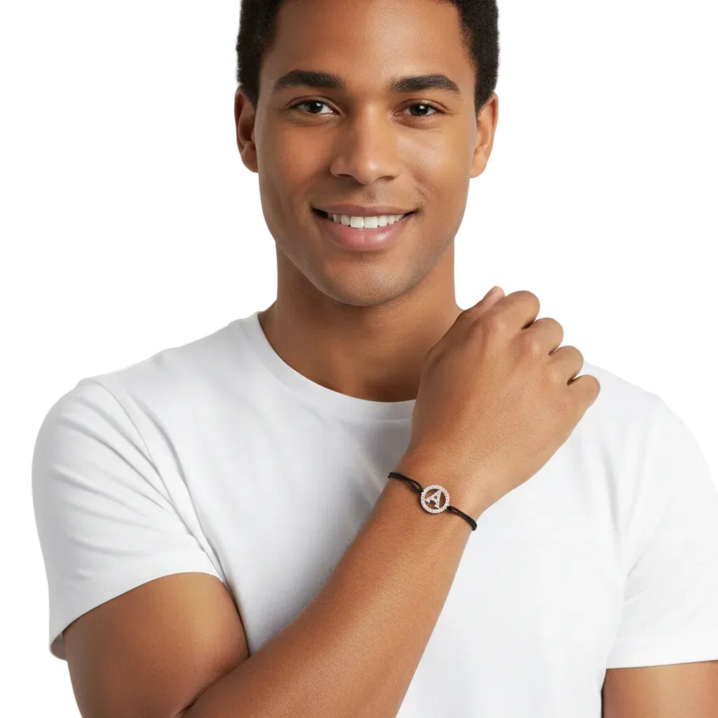 Man wearing a silver diamond-studded A initial bracelet on black cord