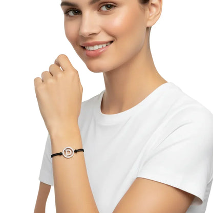 Woman wearing a diamond alphabet D bracelet on black cord, silver setting, close-up view