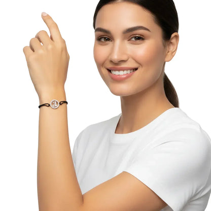 Woman wearing silver diamond E initial bracelet on black cord, isolated on white background