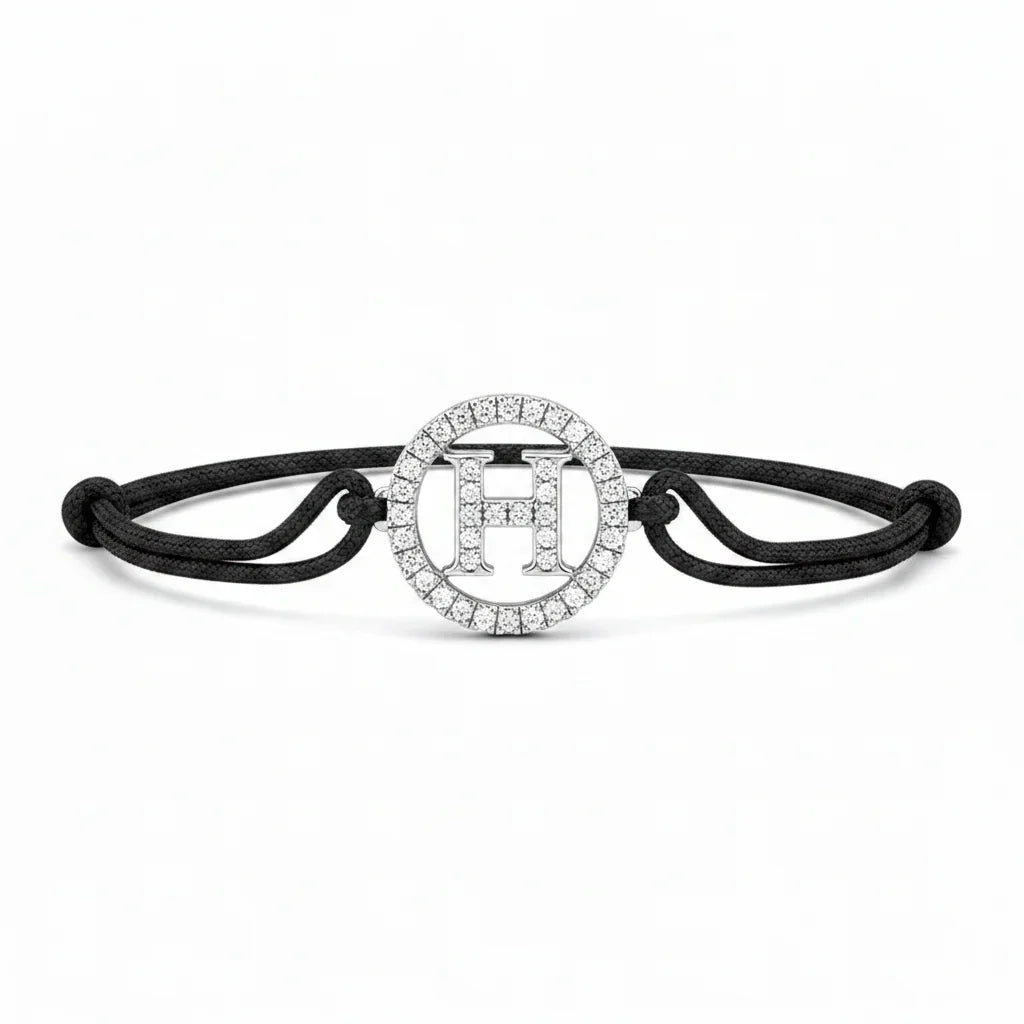 Silver diamond alphabet H bracelet with black adjustable cord on white background