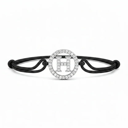Silver diamond alphabet H bracelet with black adjustable cord on white background