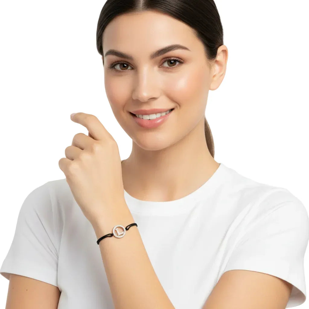 Woman wearing a silver diamond alphabet L bracelet with black adjustable cord.