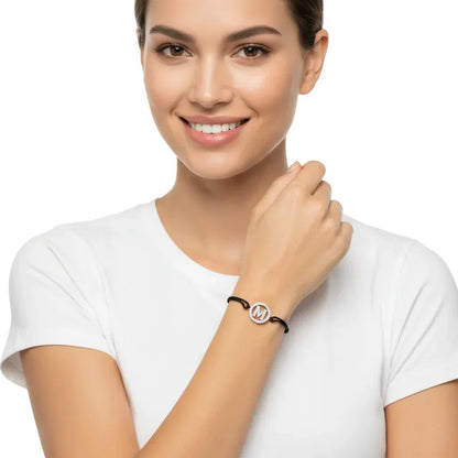 Woman wearing silver diamond initial M bracelet on black cord, minimalist jewelry