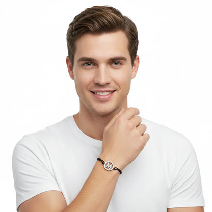 Man wearing silver diamond M alphabet bracelet on black cord, minimalist jewelry style