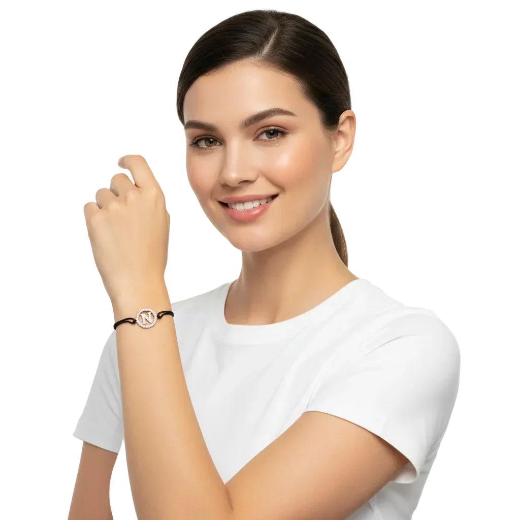 Woman wearing a silver diamond initial N bracelet with black cord on wrist