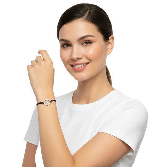 Woman wearing a silver diamond initial N bracelet with black cord on wrist
