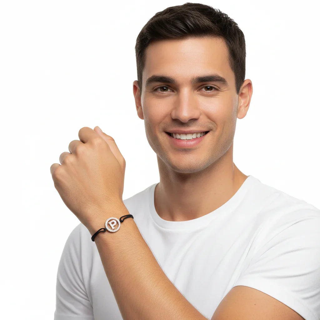 Man wearing a diamond-studded alphabet P bracelet with silver accents on a black cord