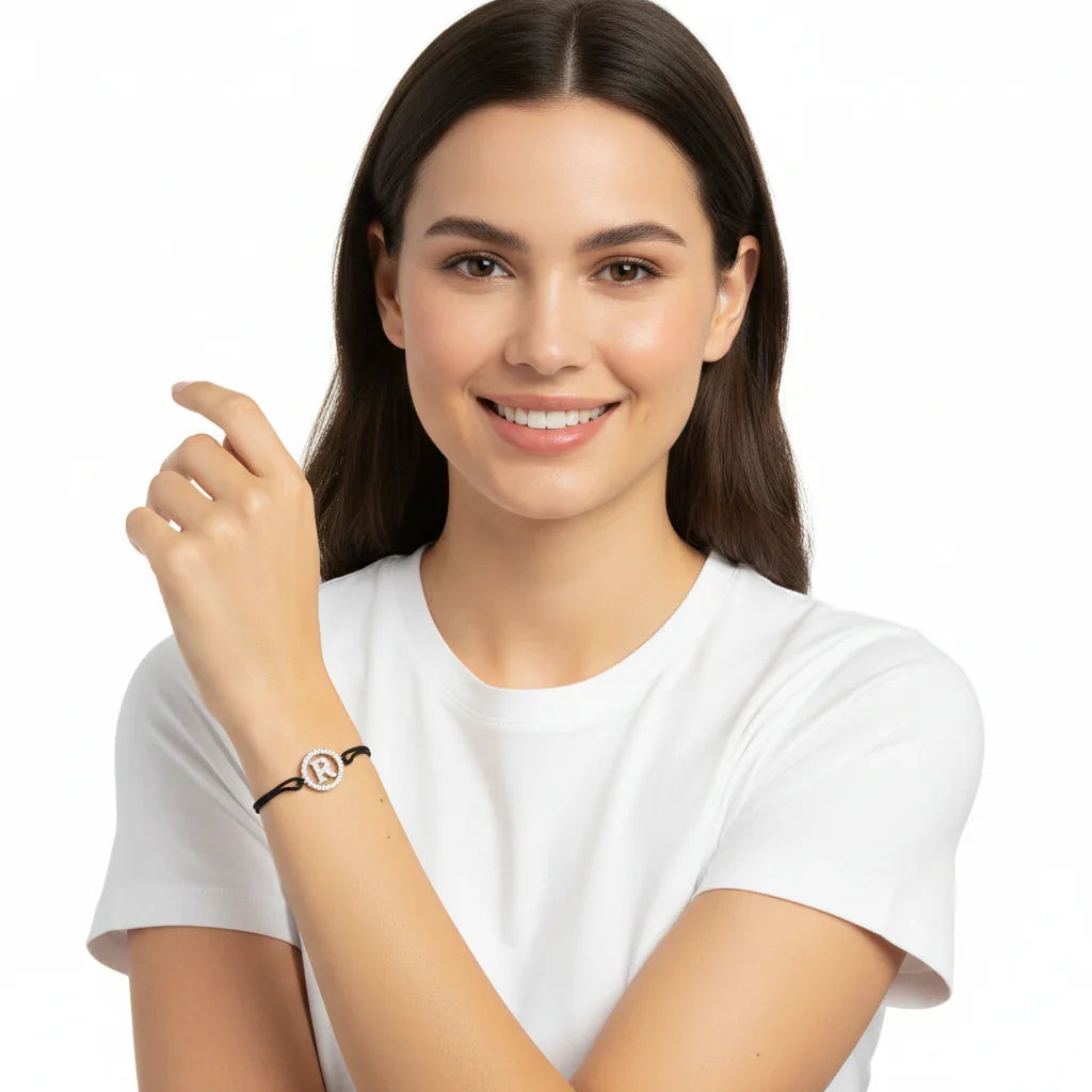 Woman wearing a silver diamond alphabet R bracelet with black cord on wrist