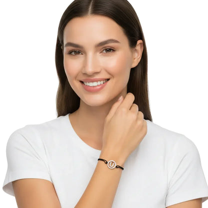 Woman wearing a silver diamond alphabet U bracelet on black cord, minimalist jewelry style