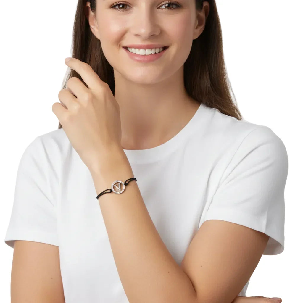 Woman wearing a silver diamond alphabet V bracelet with black cord on her wrist.