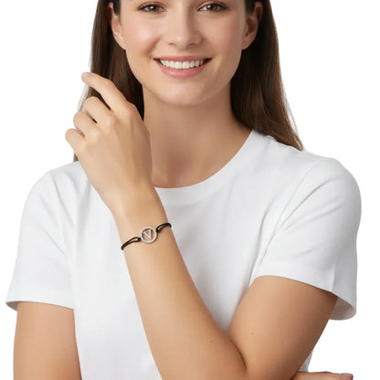Woman wearing a silver diamond alphabet V bracelet with black cord on her wrist.