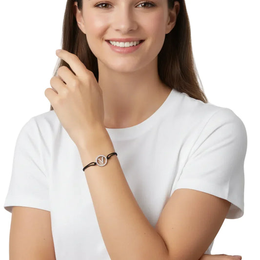 Woman wearing a silver diamond alphabet V bracelet with black cord on her wrist.