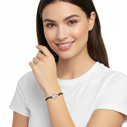 Woman wearing a diamond initial A bracelet with black band, white background