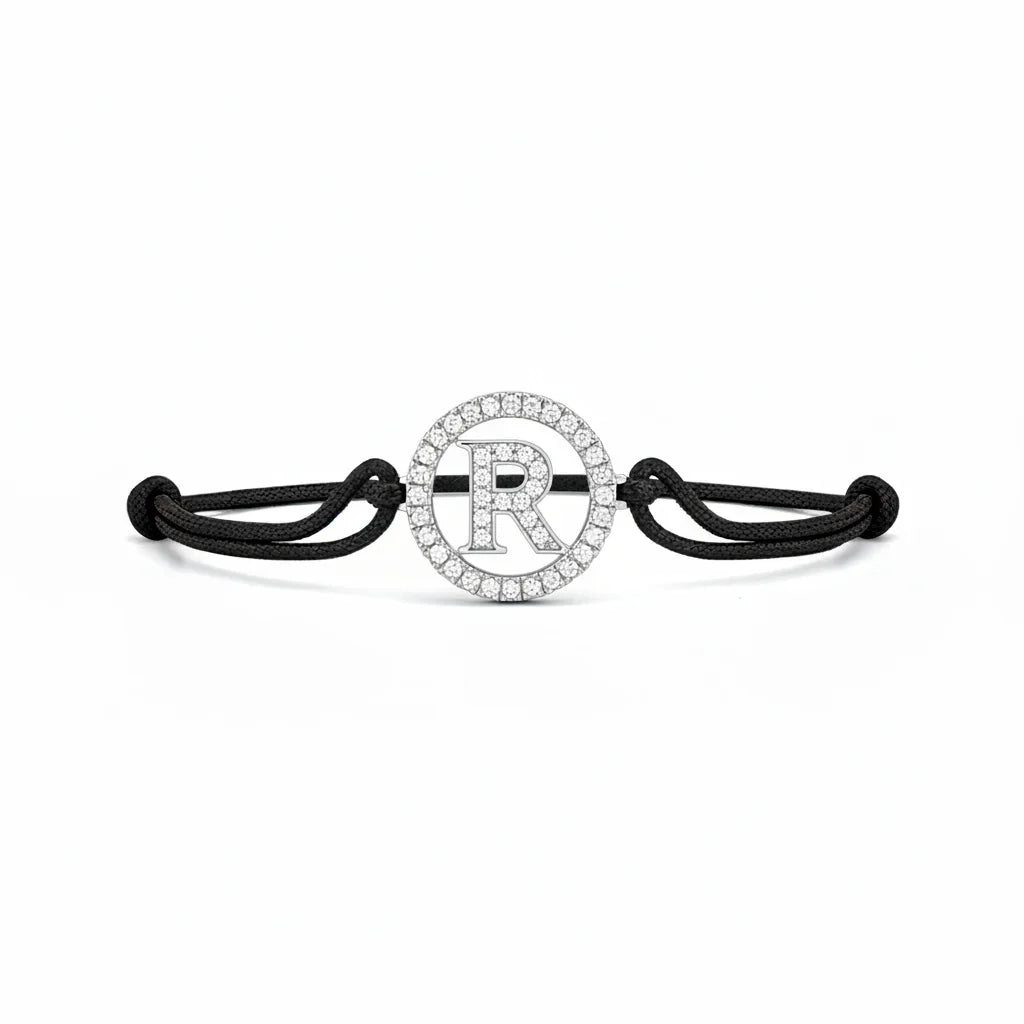 Silver diamond alphabet R bracelet with black adjustable cord on white background