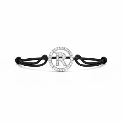 Silver diamond alphabet R bracelet with black adjustable cord on white background