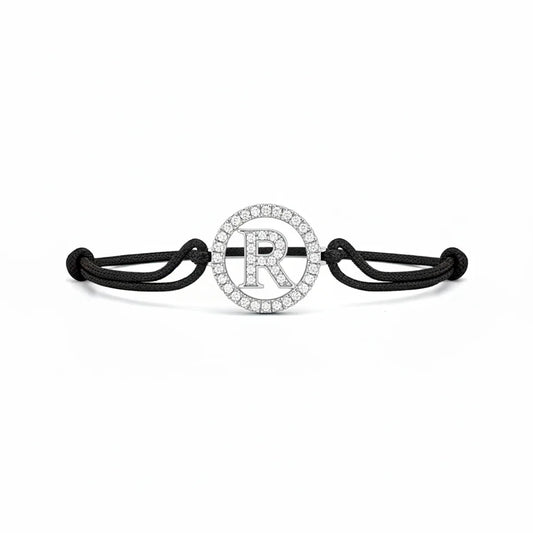 Silver diamond alphabet R bracelet with black adjustable cord on white background