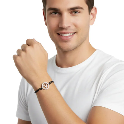 Smiling man wearing a diamond initial V bracelet on a black cord, white background